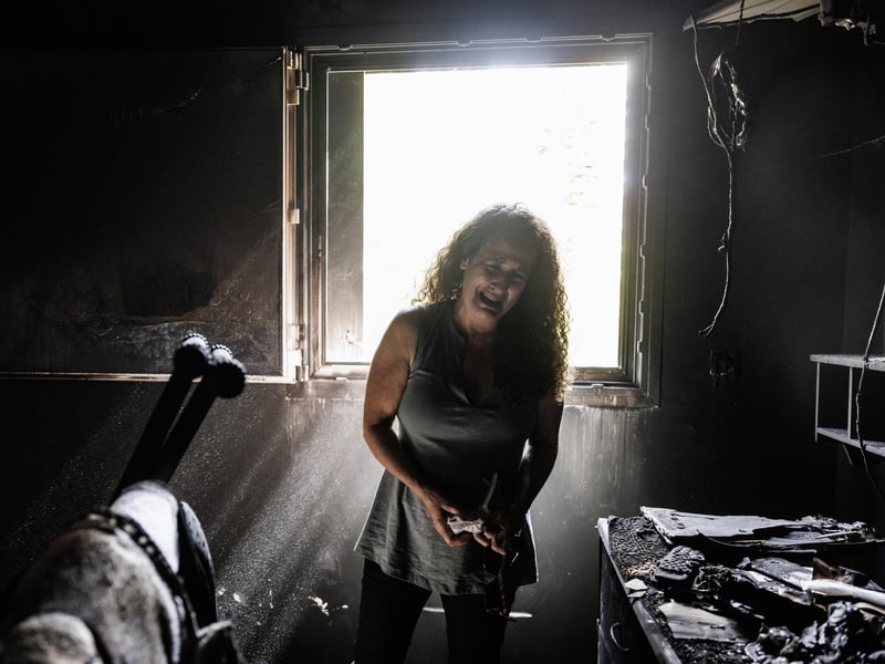 Kibbutz Nir Oz resident Hadas Kalderon, whose children have been taken hostage, and her mother and niece killed, breaks down in tears while looking through the burnt out home of her late mother Rina Sutzkever