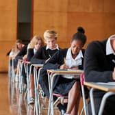 Teenage Students In Uniform Sitting Examination In School Hall