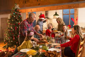 A large family are all helping serve Christmas dinner. Picture: Adobe Stock/Graham Oliver.