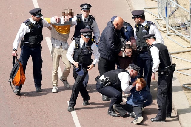 Police officers remove people who ran into the path of the royal procession on The Mall.
