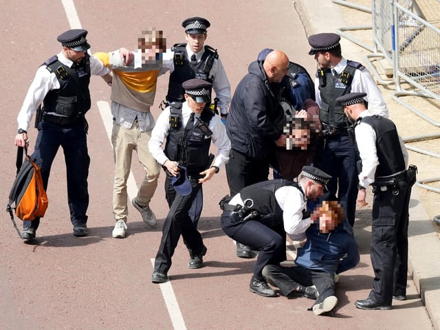 Police officers remove people who ran into the path of the royal procession on The Mall.