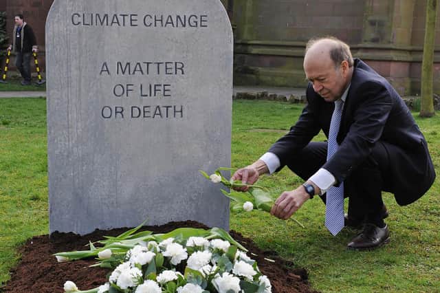 Climatologist Dr James Hansen lays flowers on a mock grave reading 'Climate change, a matter of life or death' in Coventry in 2009 (Picture: Carl de Souza/AFP via Getty Images)
