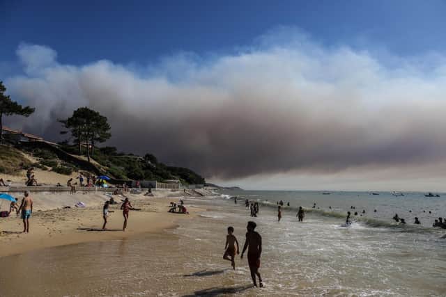 Smoke rises from La Teste-de-Buch forest as people enjoy the beach at Pyla sur mer, in southwest France (Picture: Thibaud Moritz/AFP via Getty Images)