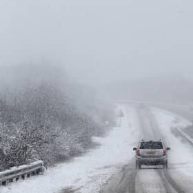 Car drives along snowy road.
