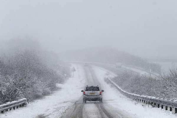 Car drives along snowy road.