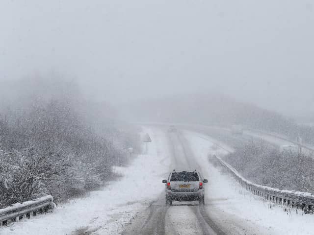 Car drives along snowy road.