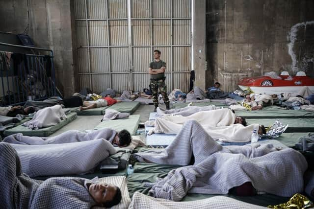 A member of the Coastguard overlooks survivors as they rest in a warehouse used as a temporary shelter, after a boat carrying dozens of migrants sank in the Ionian Sea, in Kalamata town, Greece, last week.