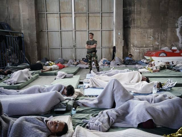A member of the Coastguard overlooks survivors as they rest in a warehouse used as a temporary shelter, after a boat carrying dozens of migrants sank in the Ionian Sea, in Kalamata town, Greece, last week.