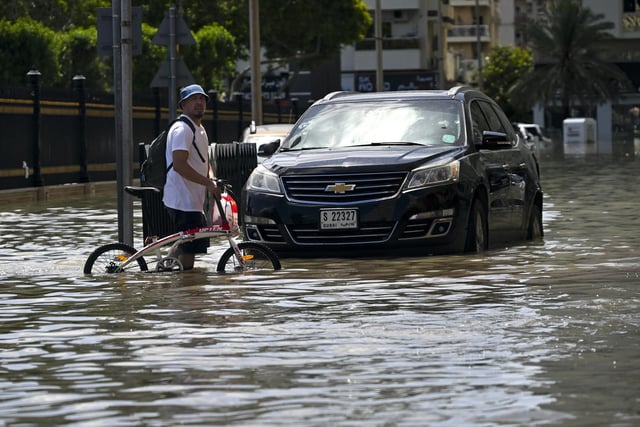 A man crosses a flooded street following heavy rains in Sharjah, UAE.