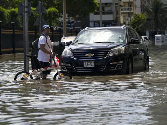 A man crosses a flooded street following heavy rains in Sharjah, UAE.