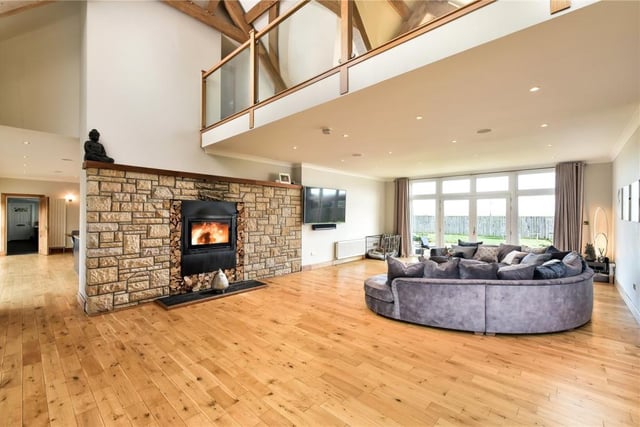 The spectacular sitting room has an impressive 22ft high ceiling and a log burner set into a feature stone wall.