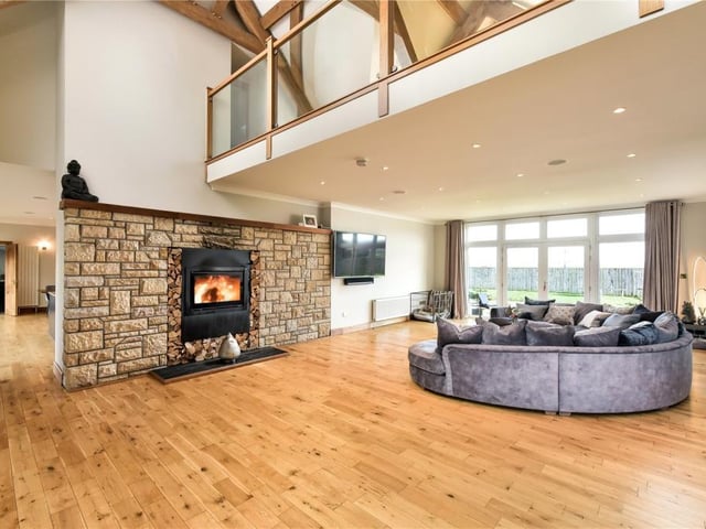 The spectacular sitting room has an impressive 22ft high ceiling and a log burner set into a feature stone wall.