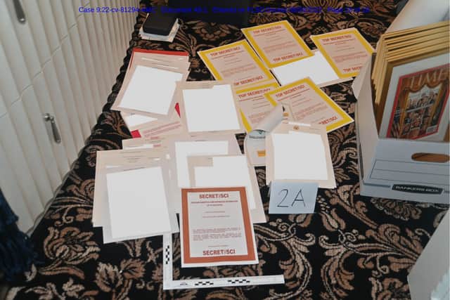 This image contained in a court filing by the Department of Justice on Aug. 30, 2022, and partially obscured by the source, shows a photo of documents seized during the Aug. 8 search by the FBI of former President Donald Trump's Mar-a-Lago estate in Florida. The Justice Department says it has uncovered efforts to obstruct its investigation into the discovery of classified records at former President Donald Trump's Florida estate. (Department of Justice via AP)
