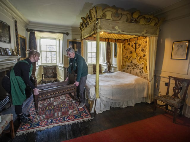 Housekeeper Lucy Whiteman and Guide Iain MacLeod position the crib of James VI (James I) at the foot of the bed where Mary Queen of Scots slept, in The Kings Room.