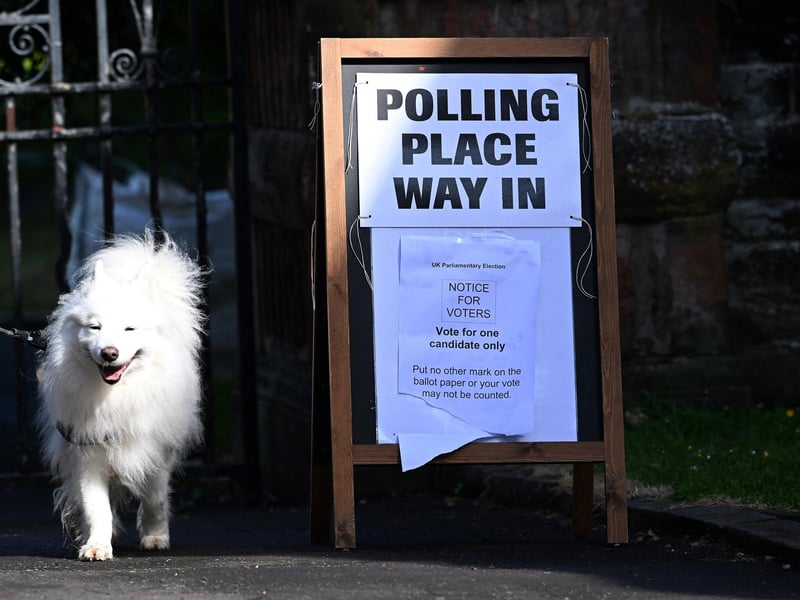 A dog is led past a polling station sign in Glasgow