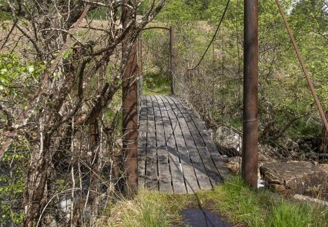 The cabin is approached via a footbridge crossing a small burn.