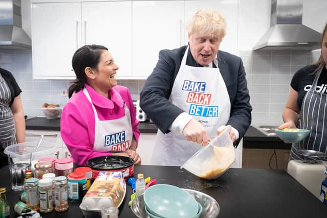 Home secretary Priti Patel looks on as Prime Minister Boris Johnson tries his hand at baking during a visit to the HideOut Youth Zone in Manchester. Picture: Stefan Rousseau-WPA Pool/Getty Images)