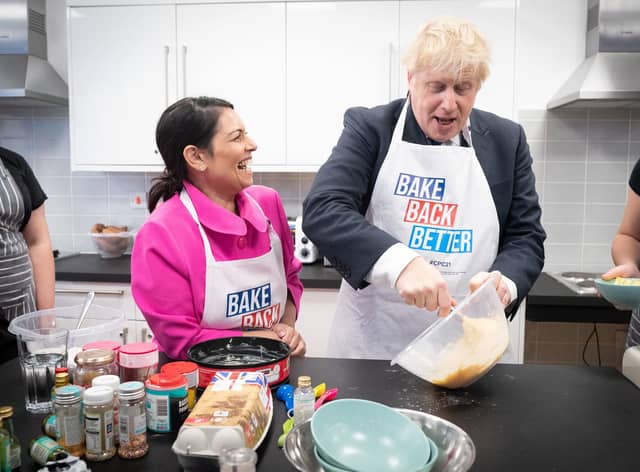 Home secretary Priti Patel looks on as Prime Minister Boris Johnson tries his hand at baking during a visit to the HideOut Youth Zone in Manchester. Picture: Stefan Rousseau-WPA Pool/Getty Images)