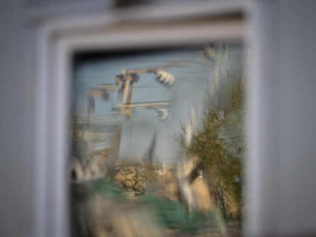 Parts of an electricity substation which was damaged in a rocket strike the previous evening are reflected in the broken window of a nearby building. Photo by Leon Neal/Getty Images.