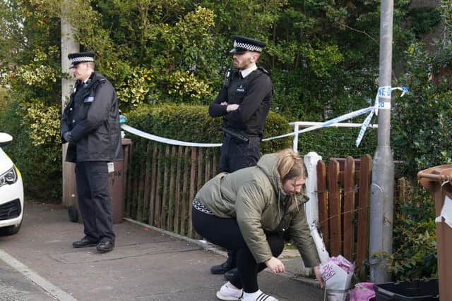 A woman lays flowers at a house in St Helens after a 17-month-old girl died after being attacked by a dog.