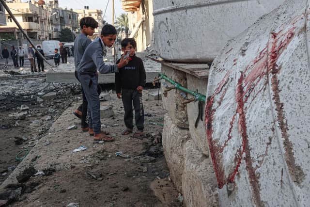 Palestinian children take pictures next to the rubble of damaged buildings following Israeli bombardment in Rafah, on the southern Gaza Strip.