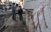 Palestinian children take pictures next to the rubble of damaged buildings following Israeli bombardment in Rafah, on the southern Gaza Strip.