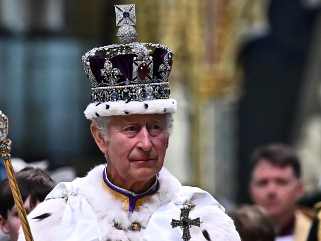 King Charles III wearing the Imperial state Crown carrying the Sovereign's Orb and Sceptre leaves Westminster Abbey after the Coronation Ceremonies. P