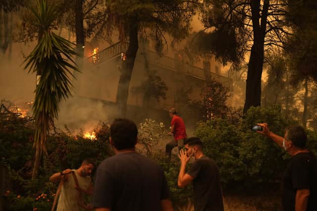Flames burn a house at Pefki village on Evia island, about 189 kilometers (118 miles) north of Athens, Greece, Sunday, Aug. 8, 2021. Pillars of billowing smoke and ash are blocking out the sun above Greece's second-largest island as a days-old wildfire devours pristine forests and triggers more evacuation alerts. (AP Photo/Petros Karadjias)