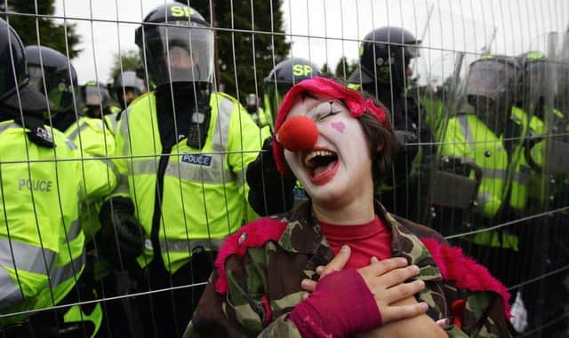 An anti-G8 protester dressed as a clown stands by a fence near Gleneagles hotel