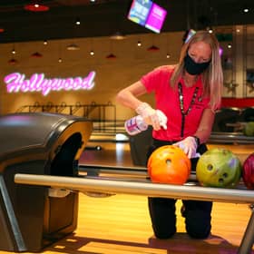 A member of staff at a Hollywood Bowl venue cleans the bowling balls as part of Covid measures. Picture: Steve Parsons/PA