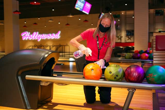 A member of staff at a Hollywood Bowl venue cleans the bowling balls as part of Covid measures. Picture: Steve Parsons/PA