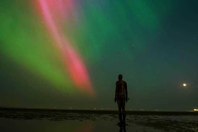The aurora borealis, also known as the northern lights, glow on the horizon at Another Place by Anthony Gormley, Crosby Beach, Liverpool , Merseyside .
