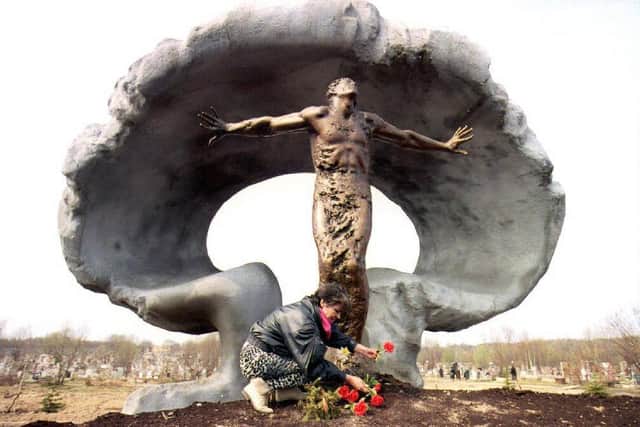 A woman places flowers at a memorial to victims of the 1986 Chernobyl nuclear power plant explosion