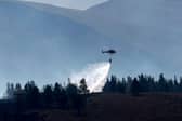 A helicopter water bombs the Cairngorm wildfire that has burned for weeks after breaking out last month (Picture: Jeff J Mitchell/Getty Images)