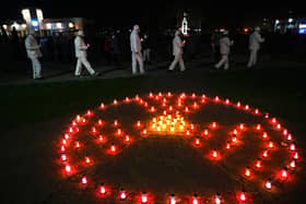 People in Slavutych, the city where the Chernobyl power station's staff lived, carry candles near a radioactivity sign at a monument to the victims of the world's worst nuclear disaster (Picture: Sergei Supinsky/AFP via Getty Images)
