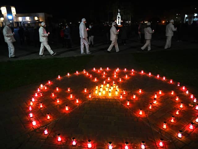 People in Slavutych, the city where the Chernobyl power station's staff lived, carry candles near a radioactivity sign at a monument to the victims of the world's worst nuclear disaster (Picture: Sergei Supinsky/AFP via Getty Images)