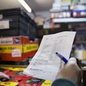 A volunteer with a packing list selecting items from it for the food parcel in the food bank warehouse