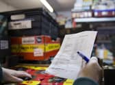A volunteer with a packing list selecting items from it for the food parcel in the food bank warehouse