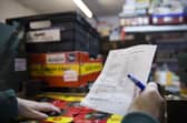 A volunteer with a packing list selecting items from it for the food parcel in the food bank warehouse