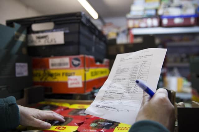 A volunteer with a packing list selecting items from it for the food parcel in the food bank warehouse
