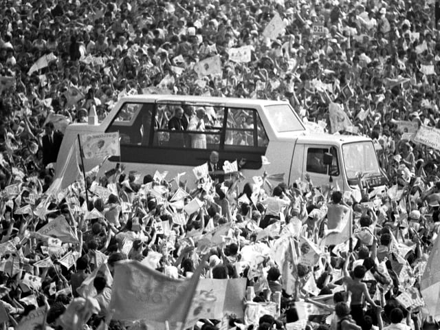 Pope John Paul II is driven through a sea of flags in the Popemobile at Bellahouston Park, in Glasgow.