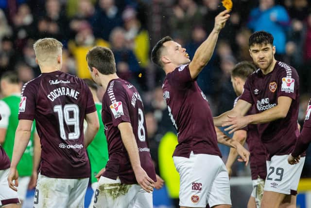 Hearts' Lawrence Shankland takes a bite of a pie that was thrown at him during the last Edinburgh derby.
