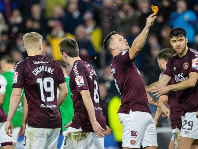 Hearts' Lawrence Shankland takes a bite of a pie that was thrown at him during the last Edinburgh derby.