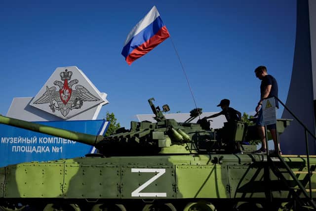 Visitors inspect a military vehicle adorned with a Russian national tricolor flag and the letter Z, which has become a symbol of support for Russian military action in Ukraine, at Patriot Park. (Photo by Natalia KOLESNIKOVA / AFP) (Photo by NATALIA KOLESNIKOVA/AFP via Getty Images)