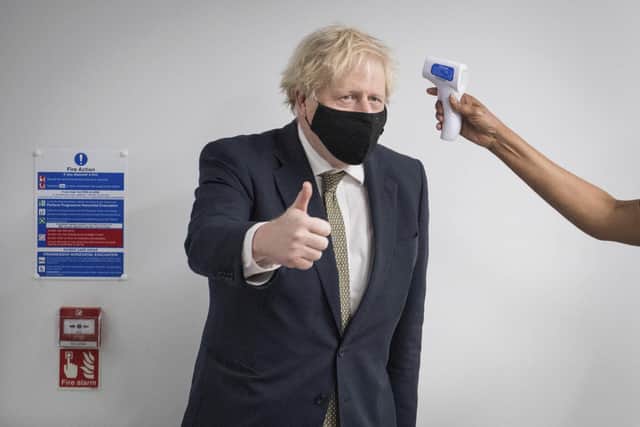 Britain's Prime Minister Boris Johnson gestures as he has his temperature checked during a visit to Chase Farm Hospital in north London. Picture: Stefan Rousseau/Pool Photo via AP