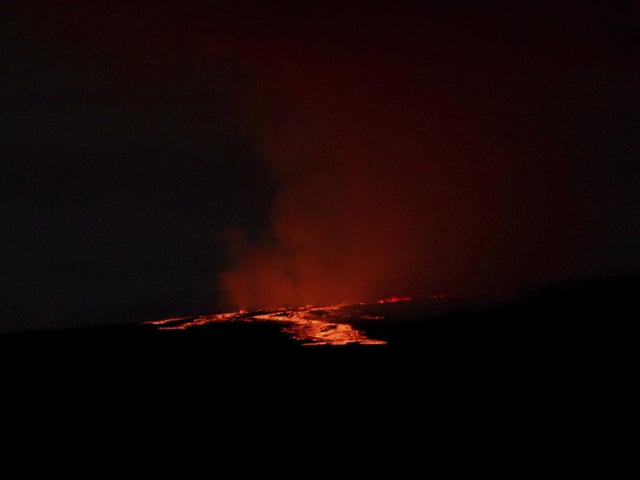 Lava pours out of the summit crater of Mauna Loa about 6:35 a.m. Monday, Nov. 28, 2022, as seen from Gilbert Kahele Recreation Area on Maunakea, Hawaii. Mauna Loa, the world’s largest active volcano, began spewing ash and debris from its summit, prompting civil defense officials to warn residents on Monday to prepare in case the eruption causes lava to flow toward communities. (Chelsea Jensen/West Hawaii Today via AP)