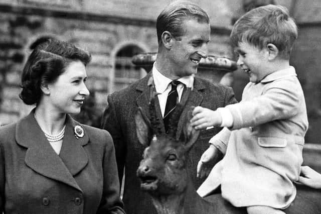 The young Prince Charles sitting on a statue watched by King George VI, Princess Elizabeth, the Duke of Edinburgh, Princess Margaret and Queen Elizabeth while on holiday at Balmoral.