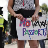 An anti-vaccination demonstrator in London holds a placard protesting against coronavirus vaccine passports