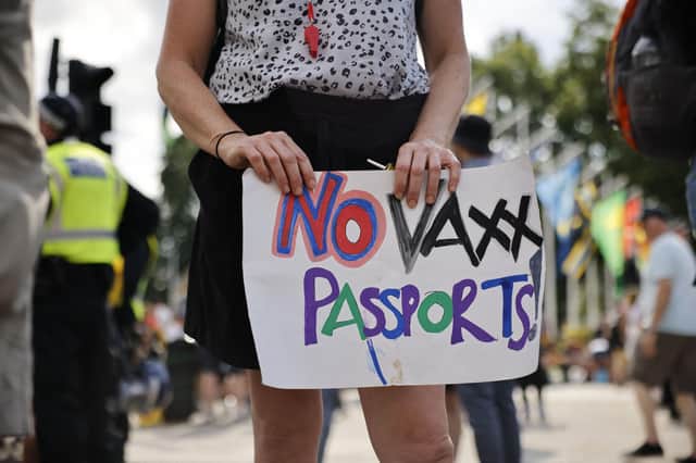 An anti-vaccination demonstrator in London holds a placard protesting against coronavirus vaccine passports