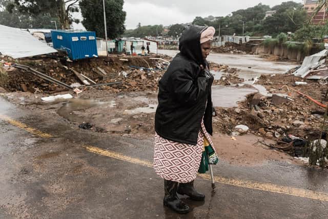 A woman in a drenched raincoat walks amid the wreckage near Durban on Tuesday as rain begins to fall once again (Picture: Rajesh Jantilal/AFP via Getty Images)